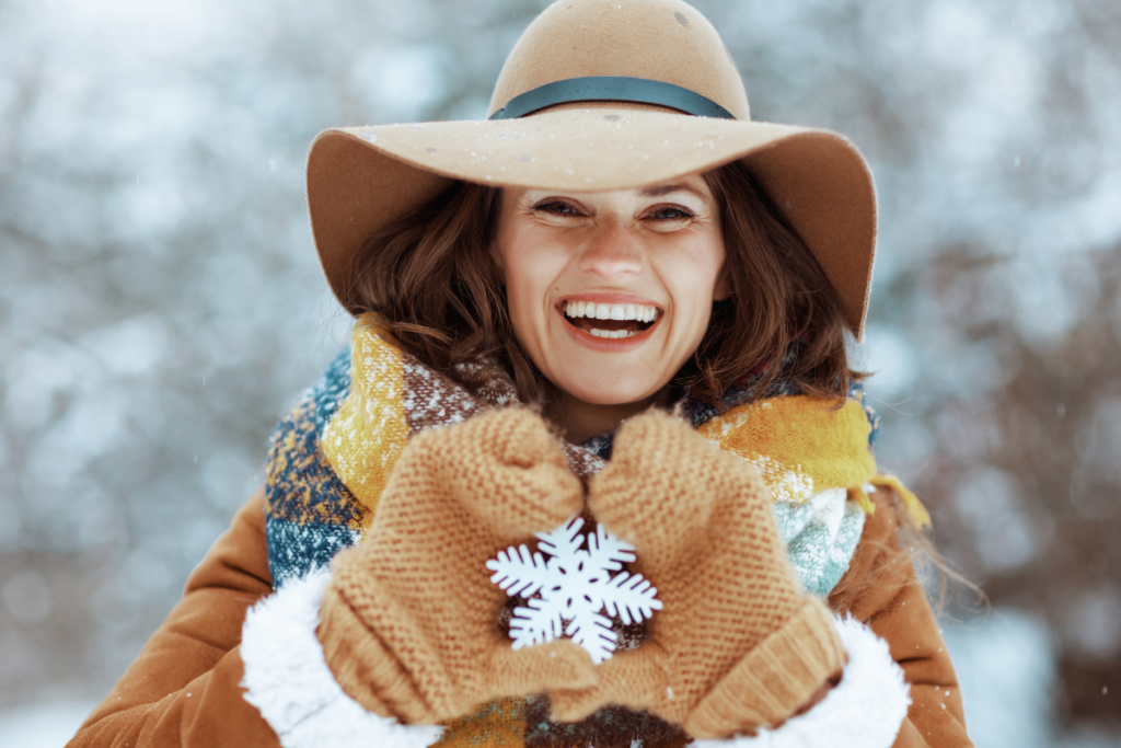 Blog Title-Seasonal Affective Disorder: Navigating the Winter Blues. Image is of a smiling woman outside in Winter holding a snowflake decoration