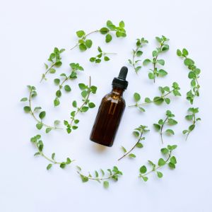 The blog title is Discover the Amazing Benefits of Organic Oregano Oil for Optimal Wellness. The image is is of a brown dropper bottle in the middle of fresh oregano leaves.