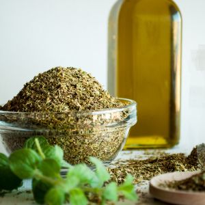 The blog title is Discover the Amazing Benefits of Organic Oregano Oil for Optimal Wellness. The image is of a bottle of olive oil with fresh and dried oregano leaves next to it.