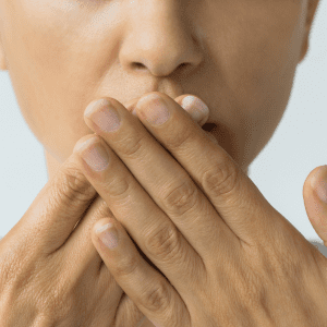 Gut Health 101 Blog Post. Image is of a woman covering her mouth with both hands.